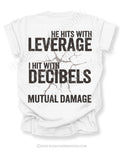 Flat lay of a white Comfort Colors t-shirt featuring the phrase "He Hits with Leverage, I Hit with Decibels" and "Mutual Damage" in a distressed football-inspired design on the back.
