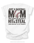 White Comfort Colors game day shirt with distressed back graphic reading “Just a Baseball Mom Who Taught My Kid How to Hit & Steal (And How Not to Get Caught)” with baseball graphic layered over MOM text