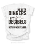 White Comfort Colors baseball mom game day shirt with distressed oversized typography reading “He Hits Dingers I Hit Decibels Both Undefeated” across the back