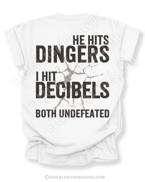 White Comfort Colors baseball mom game day shirt with distressed oversized typography reading “He Hits Dingers I Hit Decibels Both Undefeated” across the back