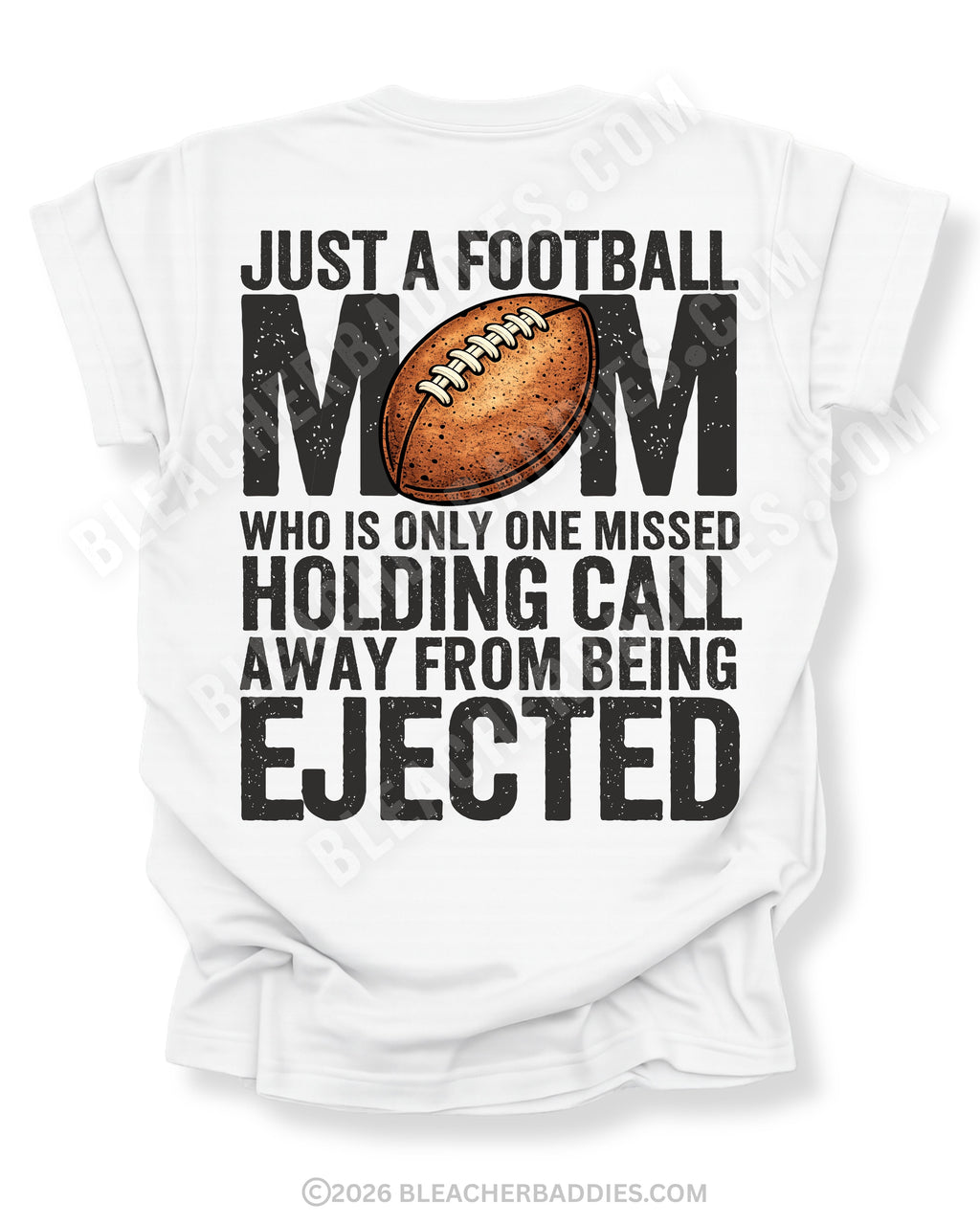 Back of white Comfort Colors football mom shirt with bold graphic text that reads “Just a football mom who is only one missed holding call away from being ejected,” featuring a distressed football design centered on the shirt.