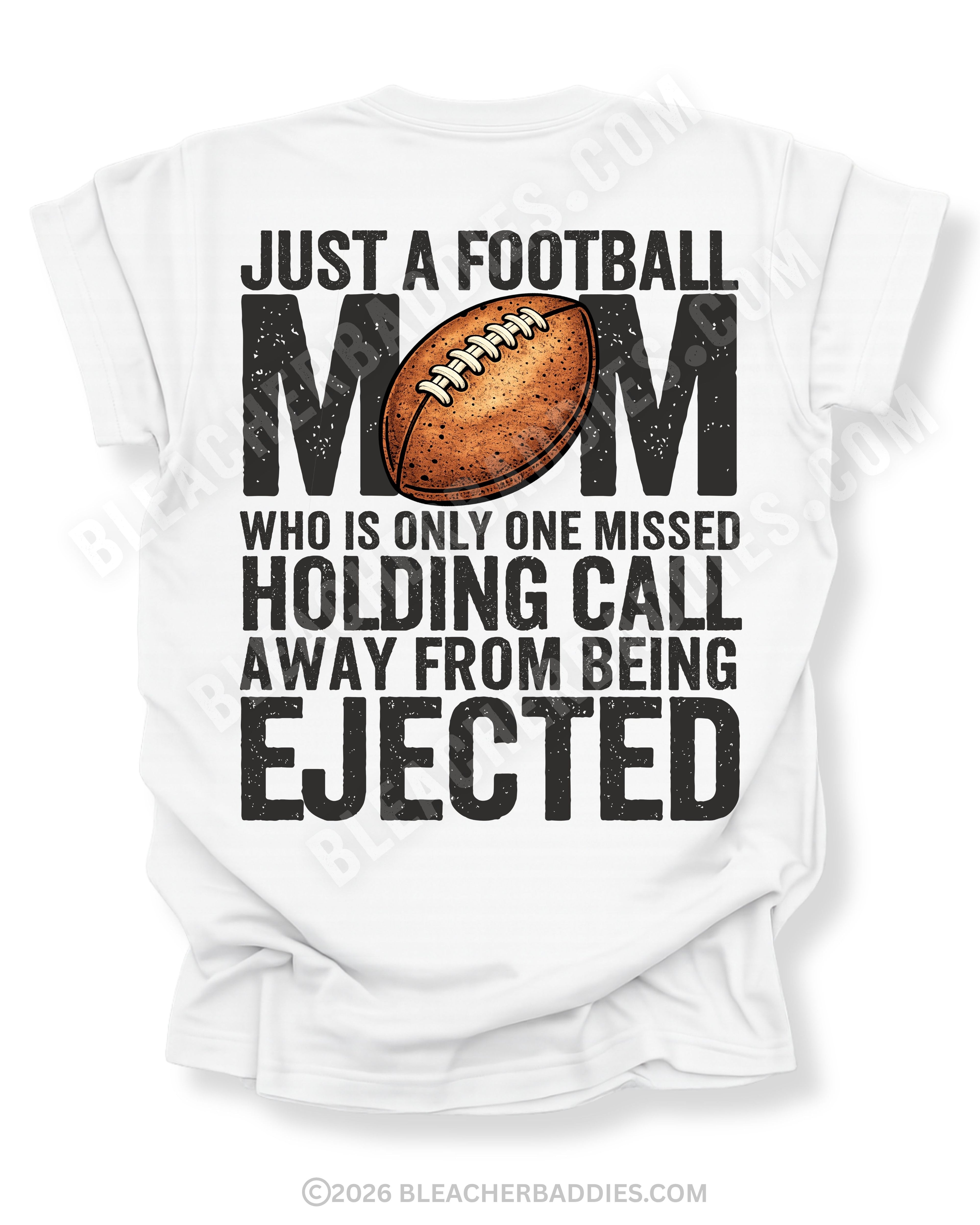 Back of white Comfort Colors football mom shirt with bold graphic text that reads “Just a football mom who is only one missed holding call away from being ejected,” featuring a distressed football design centered on the shirt.
