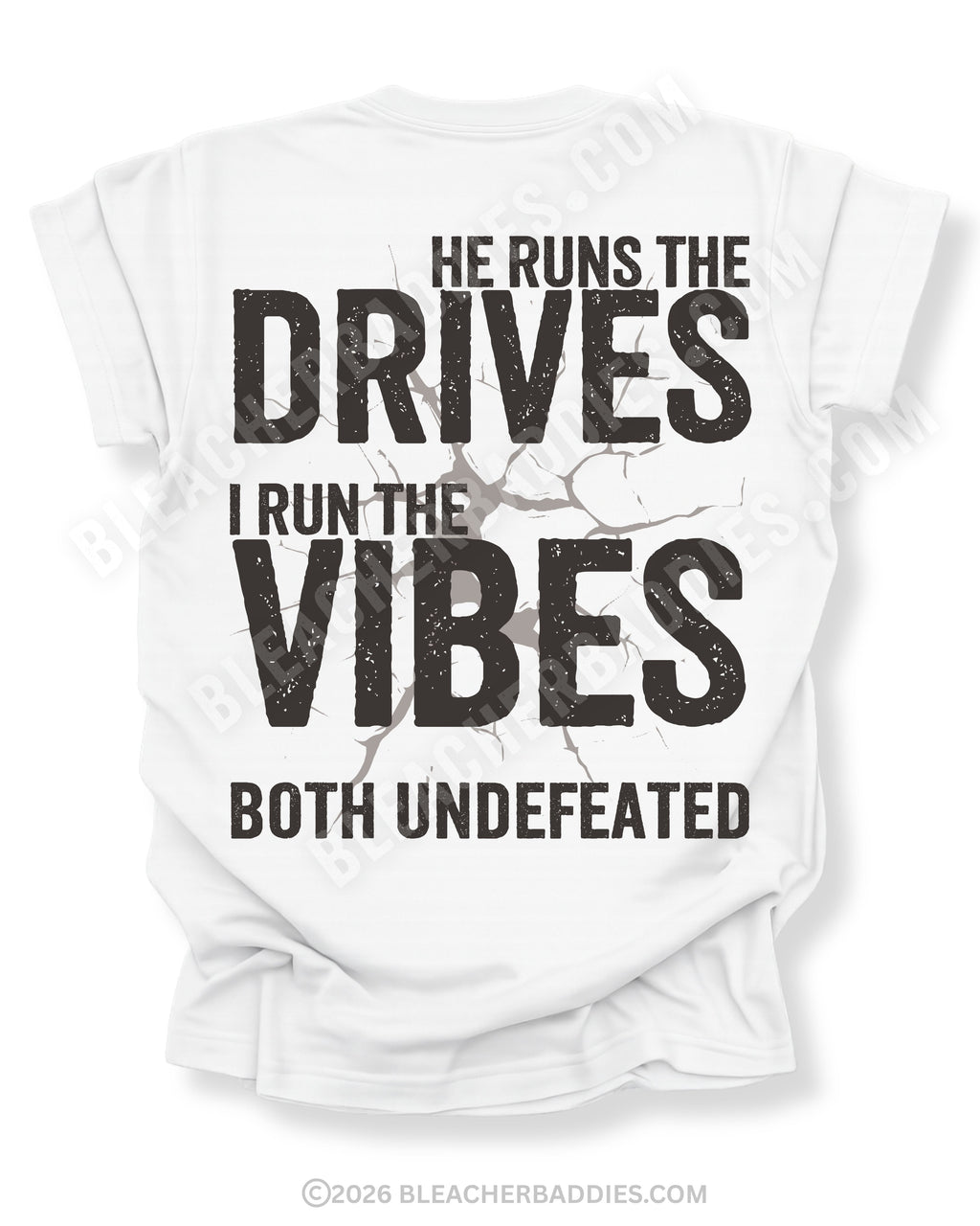 White Comfort Colors football mom shirt featuring the phrase "He Runs the Drives I Run the Vibes Both Undefeated" in distressed black typography with a cracked background graphic.