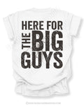 White football mom game day shirt with bold distressed black text reading “Here for the big guys” with cracked graphic behind the lettering