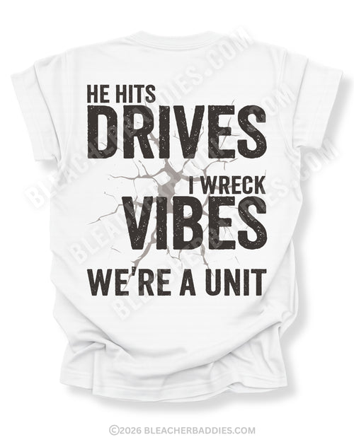 White Comfort Colors baseball mom shirt with distressed oversized back graphic reading “He Hits Drives I Wreck Vibes We’re A Unit” in bold black typography with cracked background effect and BleacherBaddies.com watermark across design.