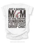 White Comfort Colors game day shirt with distressed back graphic reading “Just a Baseball Mom Out Here Surviving Sunburns & The Team Parents Group Chat” with baseball graphic layered over MOM text
