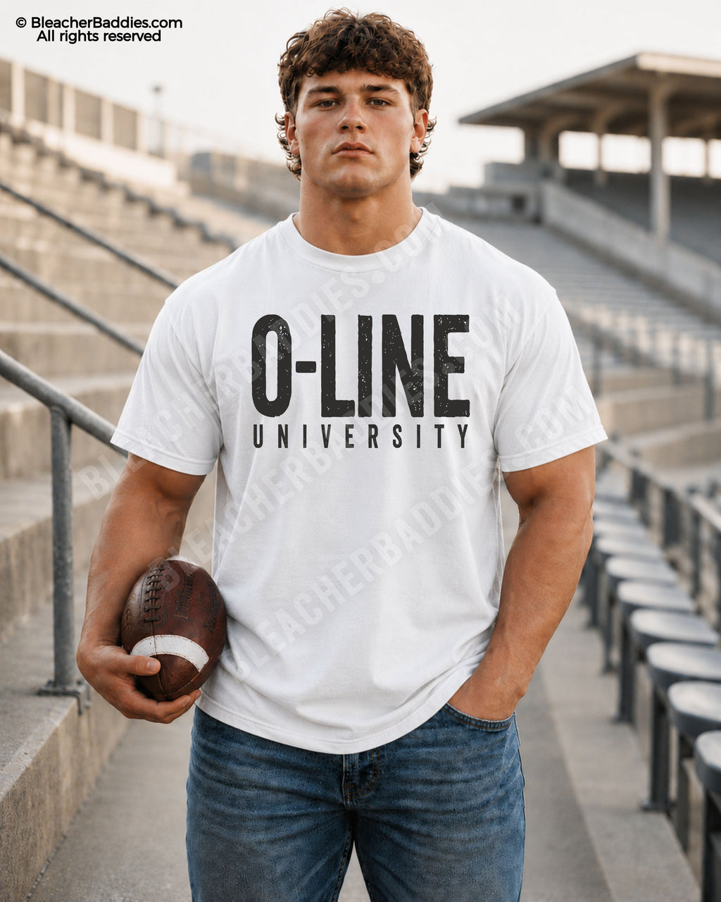 Male football player model wearing a white Comfort Colors “O-Line University” football shirt with bold distressed black typography while holding a football in stadium bleachers.